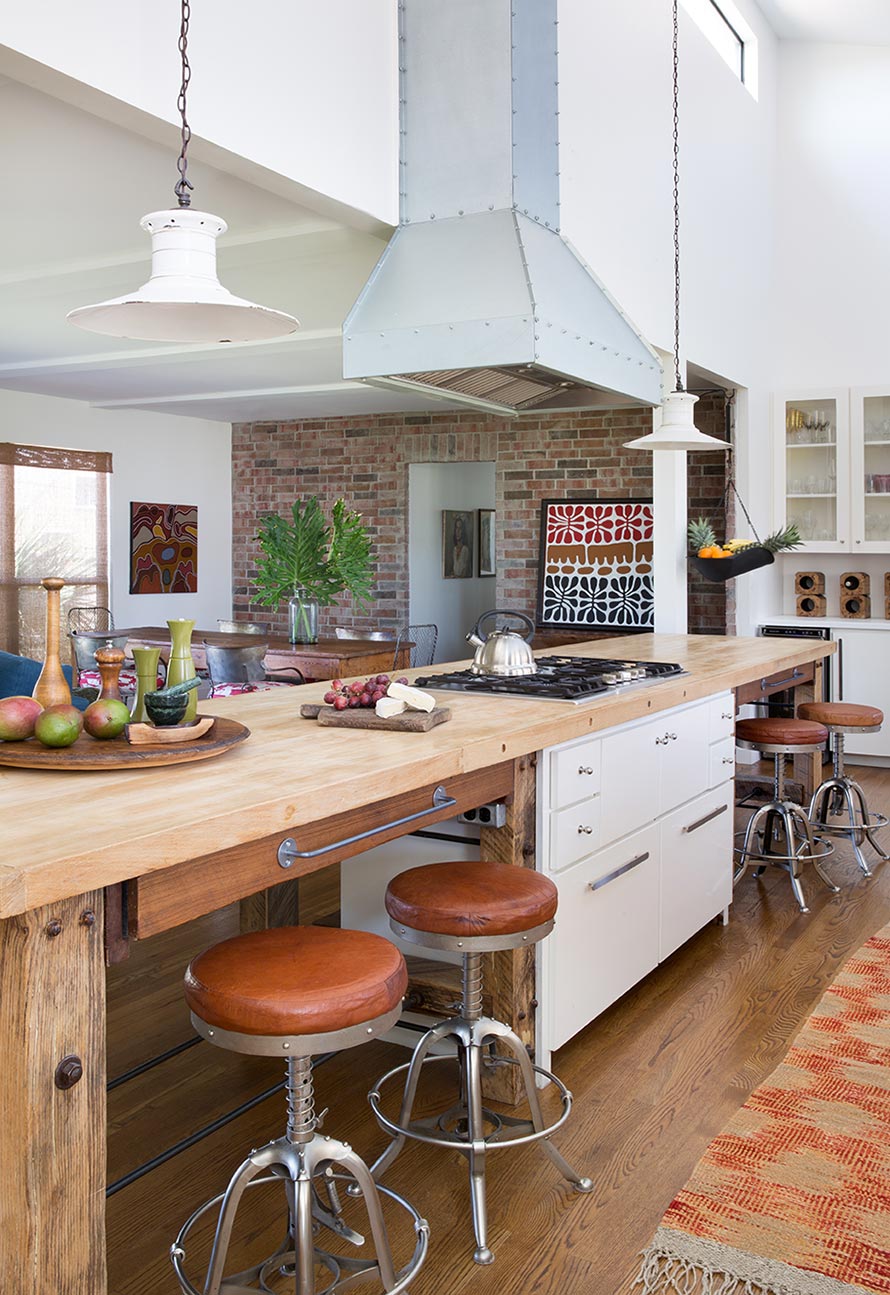 Coastal Bungalow open kitchen with white antique light fixtures and light wood countertops.