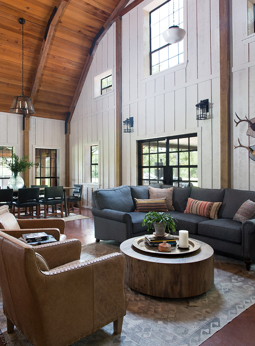 Sitting area of a river cabin with tall ceilings and grey l-shaped couch.