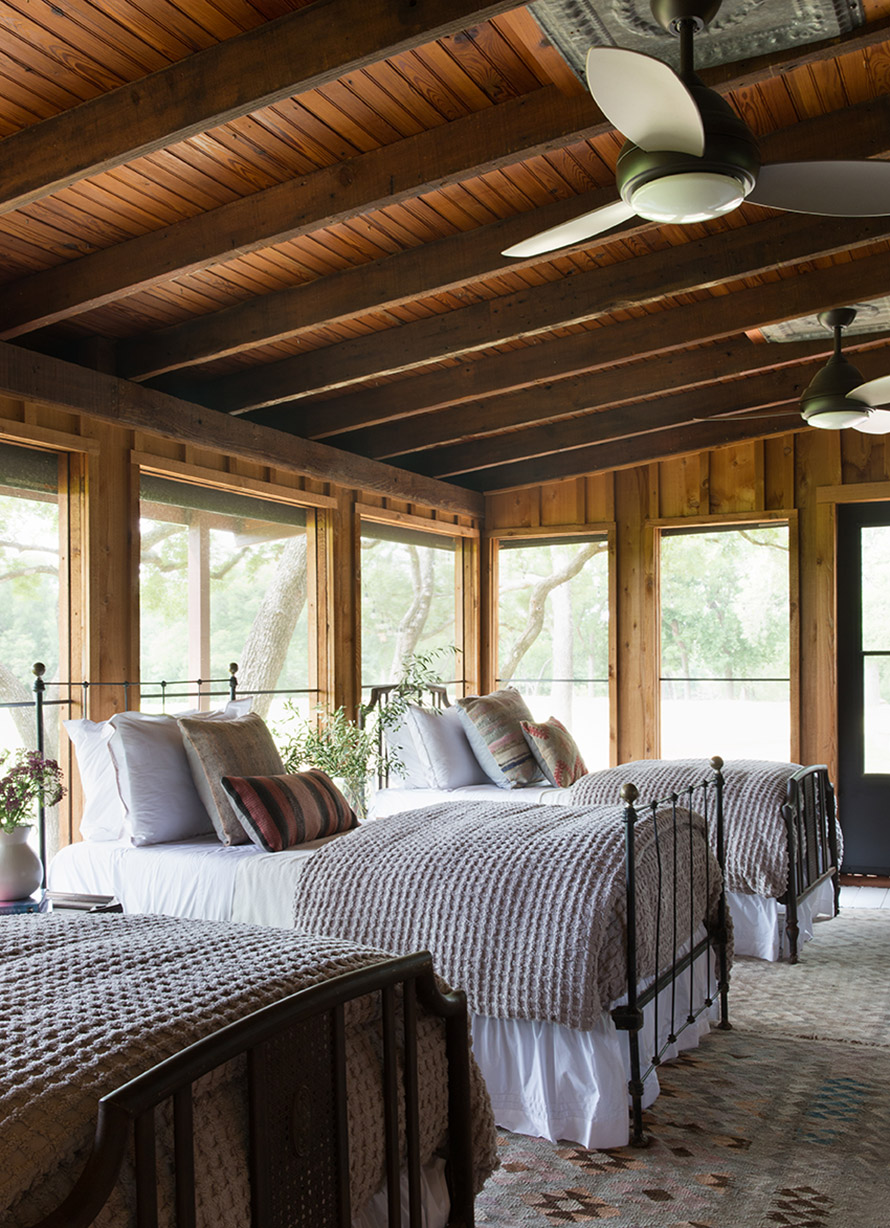 River cabin with three beds with white bedspreads and light grey throws.