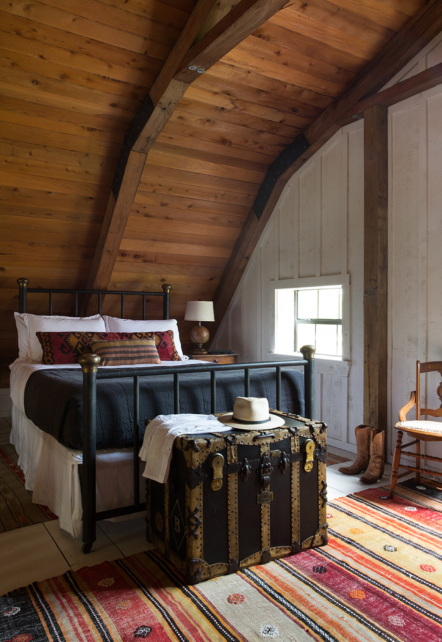 Bedroom with antique chest and rug and wood panels on the wall.