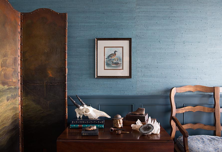 Blue textured wall with a duck painting and a small table with miscellaneous objects.