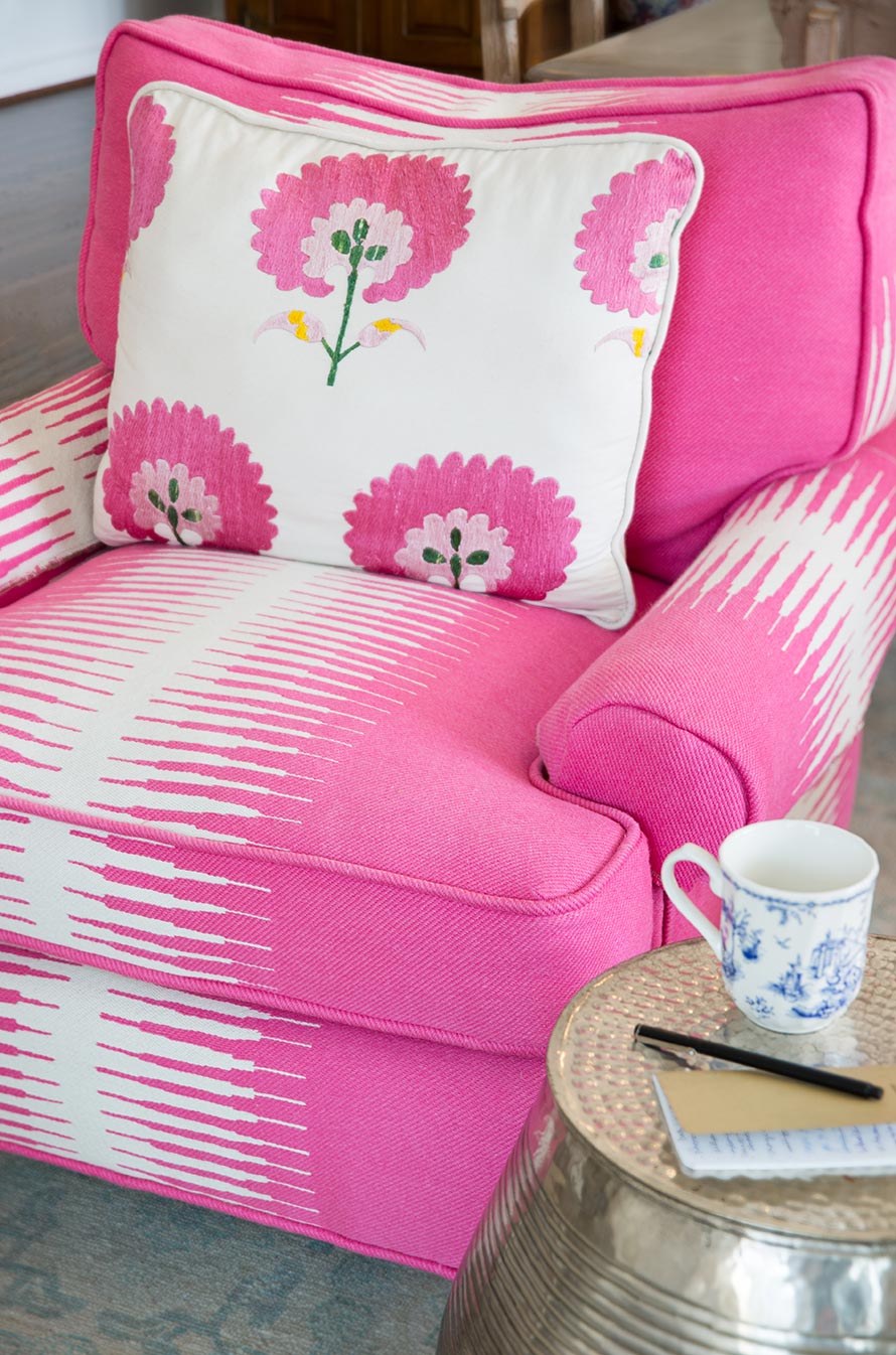 Hot pink and white chair with a throw pillow with white and pink flowers.