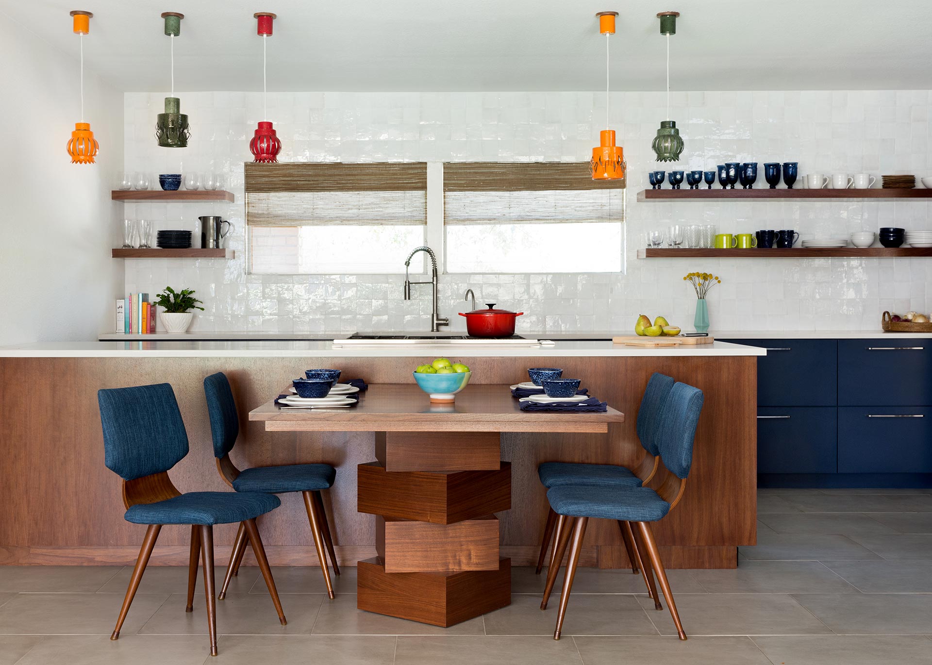 Kitchen project. Colorful light fixtures, white countertops, blue cabinets, open wood shelving, white tile backsplash designed by Round Table Design.  